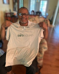 a man holding up a t - shirt that says bod squad