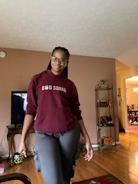 a woman wearing a maroon hoodie in a living room